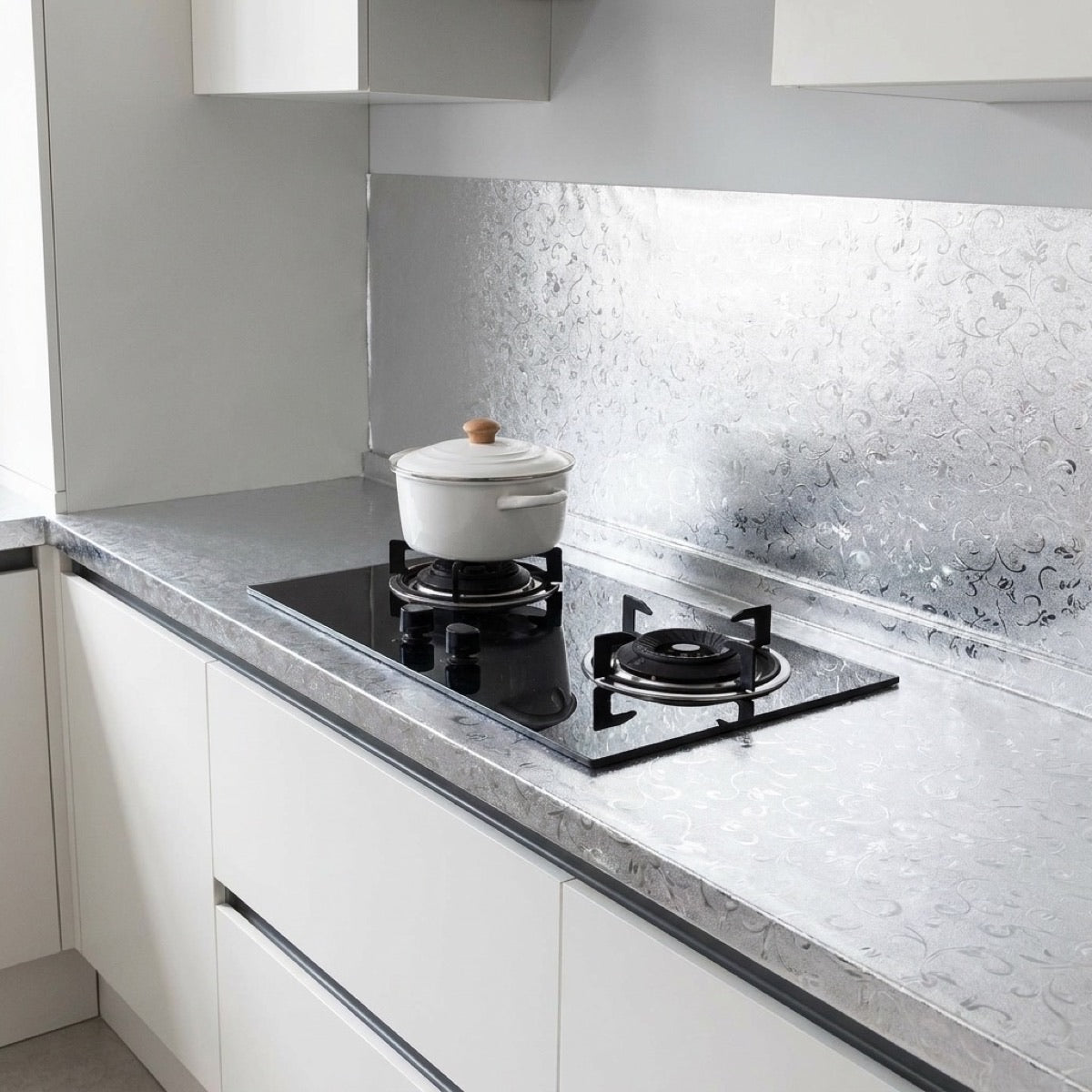 Adhésif cuisine anti-huile aluminium brossé posé sur le plan de travail et derrière les plaques de cuisson